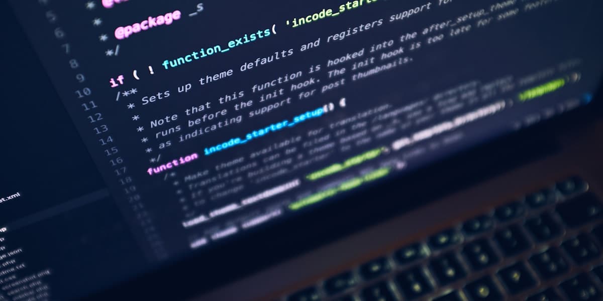 Source code on a dark editor screen above a keyboard.