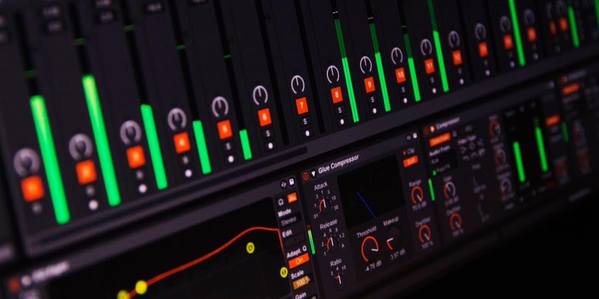 An audio mixing console with lit level meters in a control room.